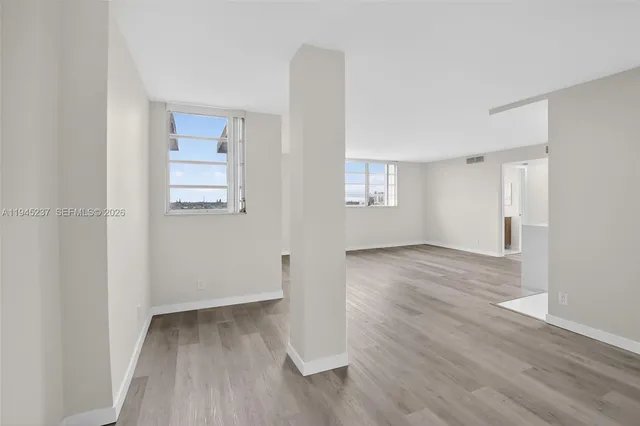 an empty room with wooden floor and windows