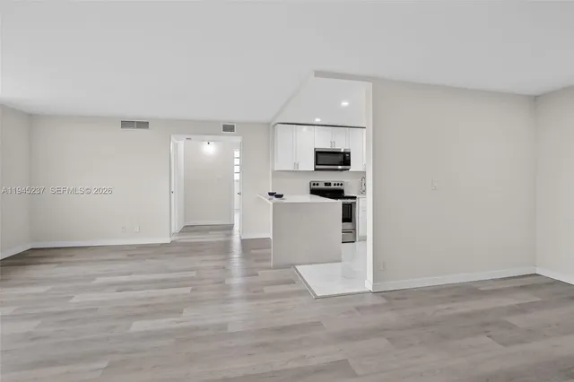 a view of kitchen with white cabinets and refrigerator