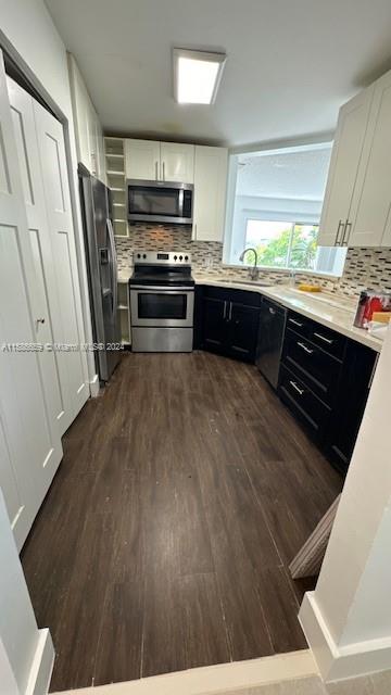 a kitchen with stainless steel appliances a stove a sink a refrigerator and wooden floors