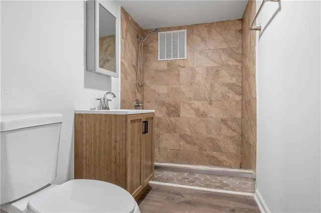 a bathroom with a sink a toilet a mirror and shower