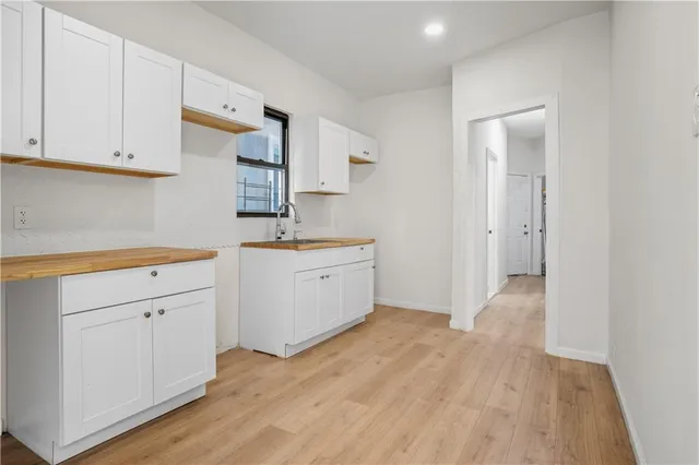 a view of a kitchen with white cabinets and wooden floor