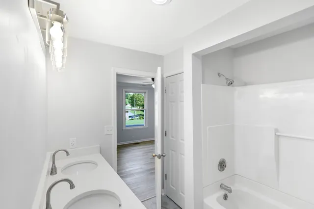 a bathroom with a tub shower vanity and a sink