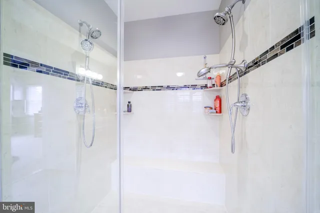 a bathroom with a granite countertop toilet a sink a mirror a window and a shower