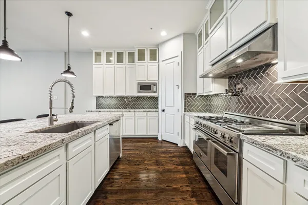 a kitchen with stainless steel appliances granite countertop a sink stove and cabinets