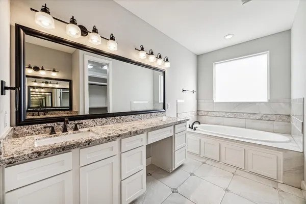 a bathroom with a granite countertop sink mirror and bathtub