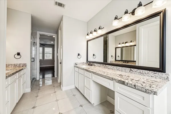 a bathroom with a granite countertop double vanity sink and a mirror