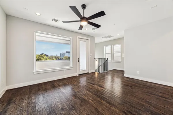 a view of an empty room with a window and wooden floor
