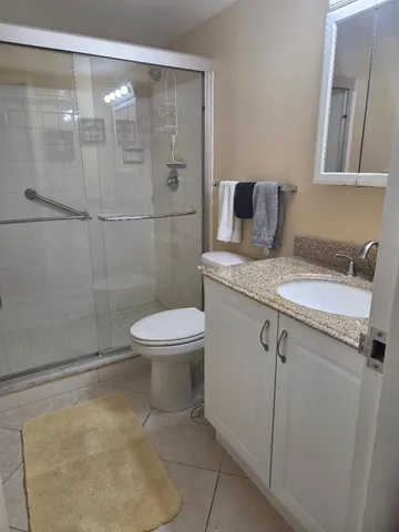 a bathroom with a granite countertop sink toilet and shower