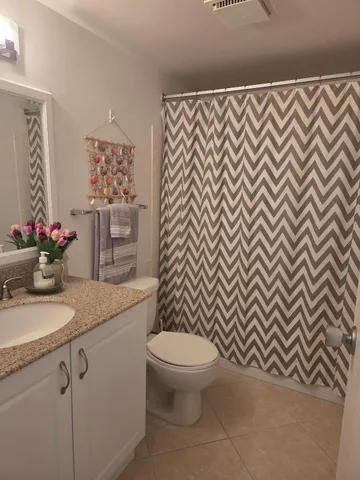 a bathroom with a granite countertop sink and a toilet