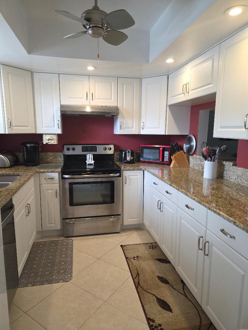 2950 Southeast Ocean Boulevard, Unit 1317 Stuart, FL 34996 - Photo 7 of 19 a kitchen with granite countertop a stove sink and cabinets
