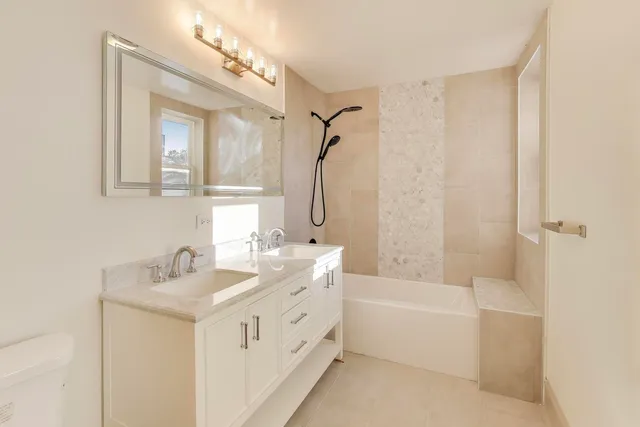 a bathroom with a double vanity sink a mirror a bathtub and shower
