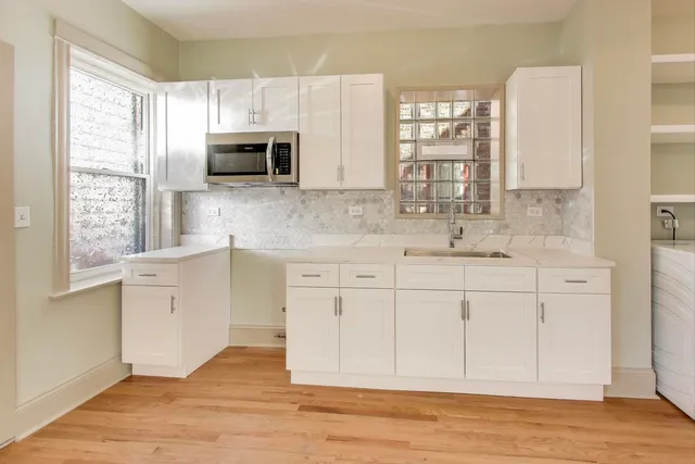 a kitchen with stainless steel appliances white cabinets and a window