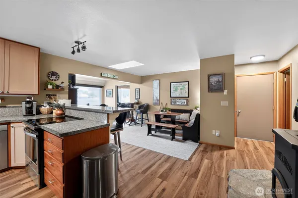 a open kitchen with granite countertop a sink dishwasher a stove and refrigerator with wooden floor