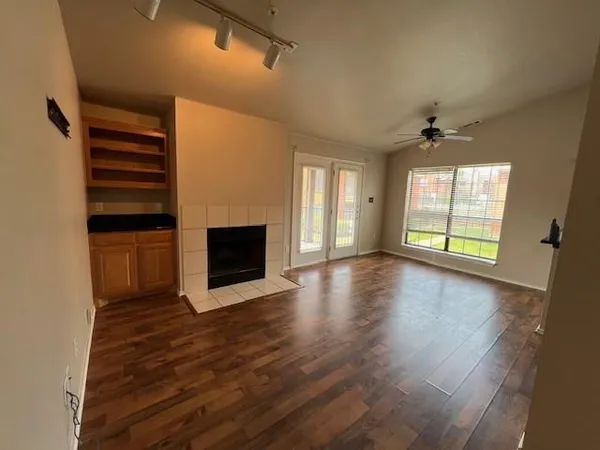 an empty room with wooden floor fireplace and windows