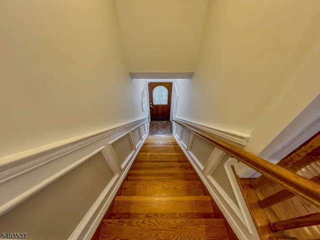 a hallway with stairs and wooden floor
