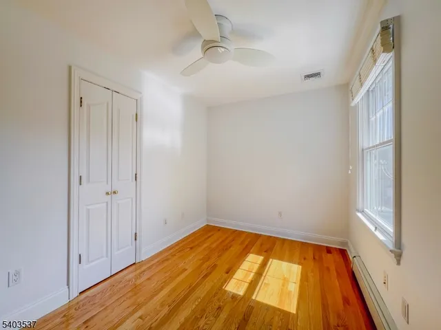 a view of empty room with wooden floor and fan