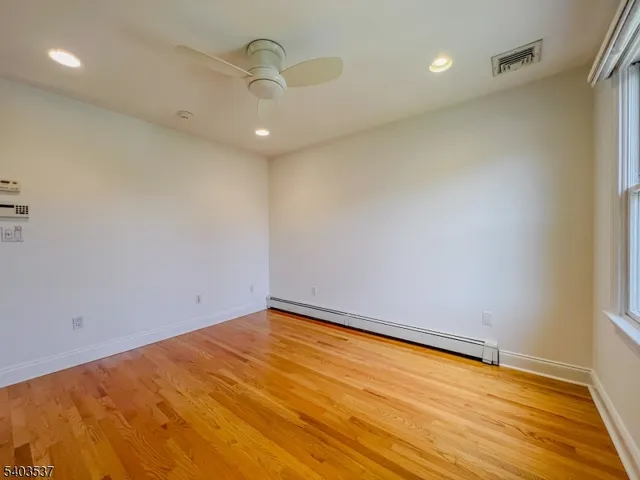 an empty room with wooden floor and fan