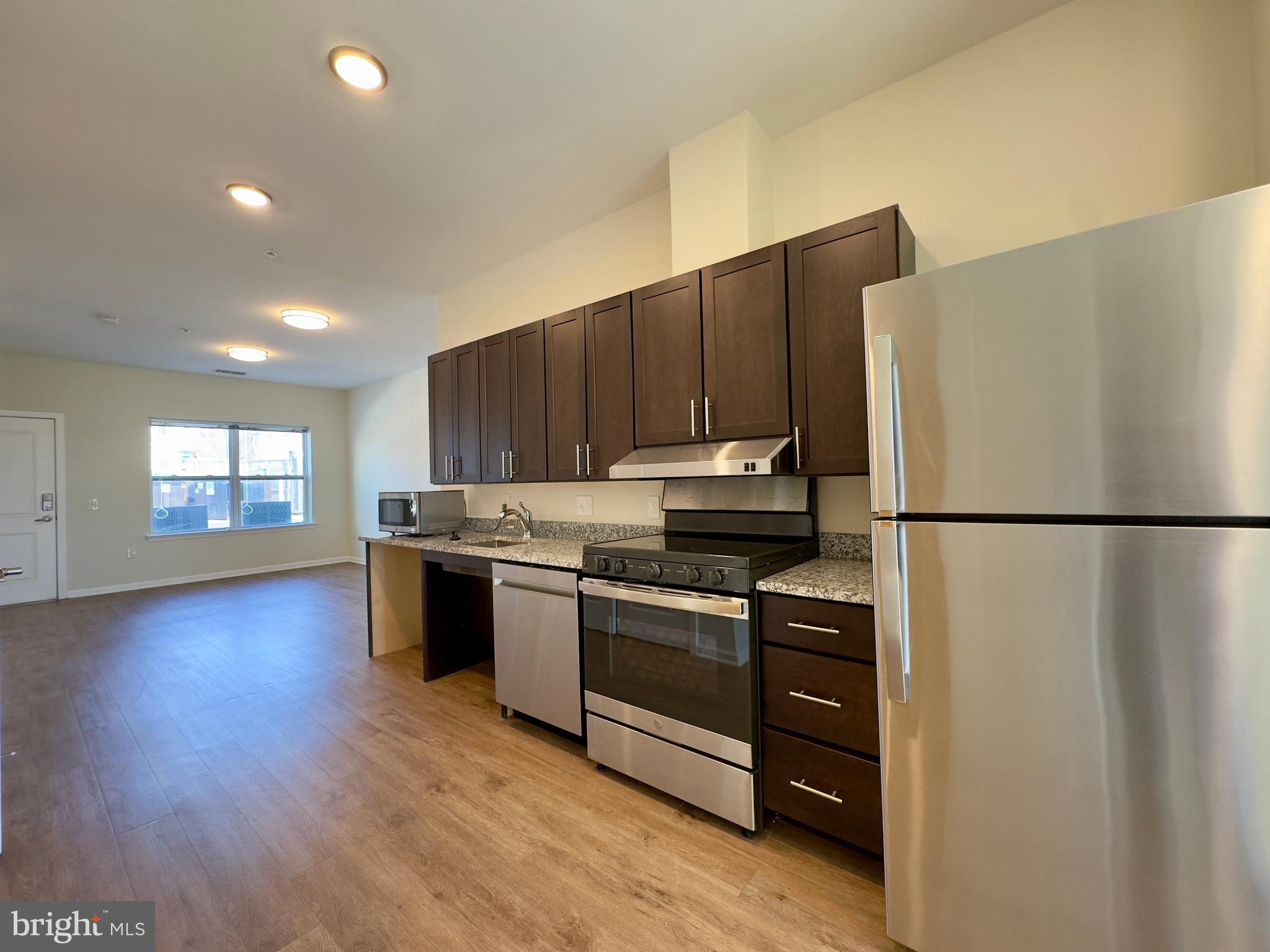 5902 Arizona Avenue, Unit 5902A Baltimore, MD 21206 - Photo 6 of 13 a kitchen with stainless steel appliances granite countertop a refrigerator stove a sink and a oven with wooden floor