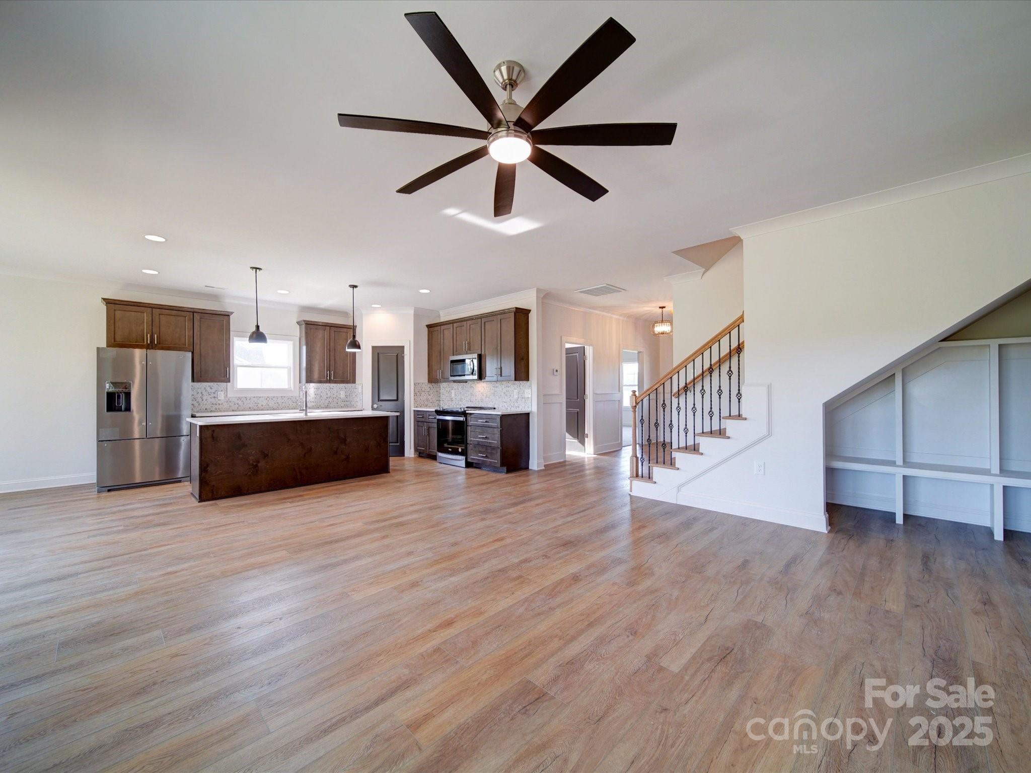 220 Lawyers Road Monroe, NC 28110 - Photo 8 of 36 a view of a livingroom with a kitchen island wooden floor and a ceiling fan