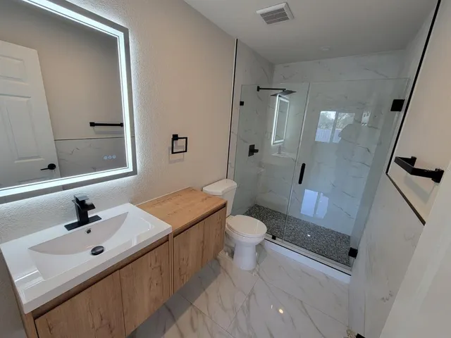 a bathroom with a sink a toilet a mirror and shower