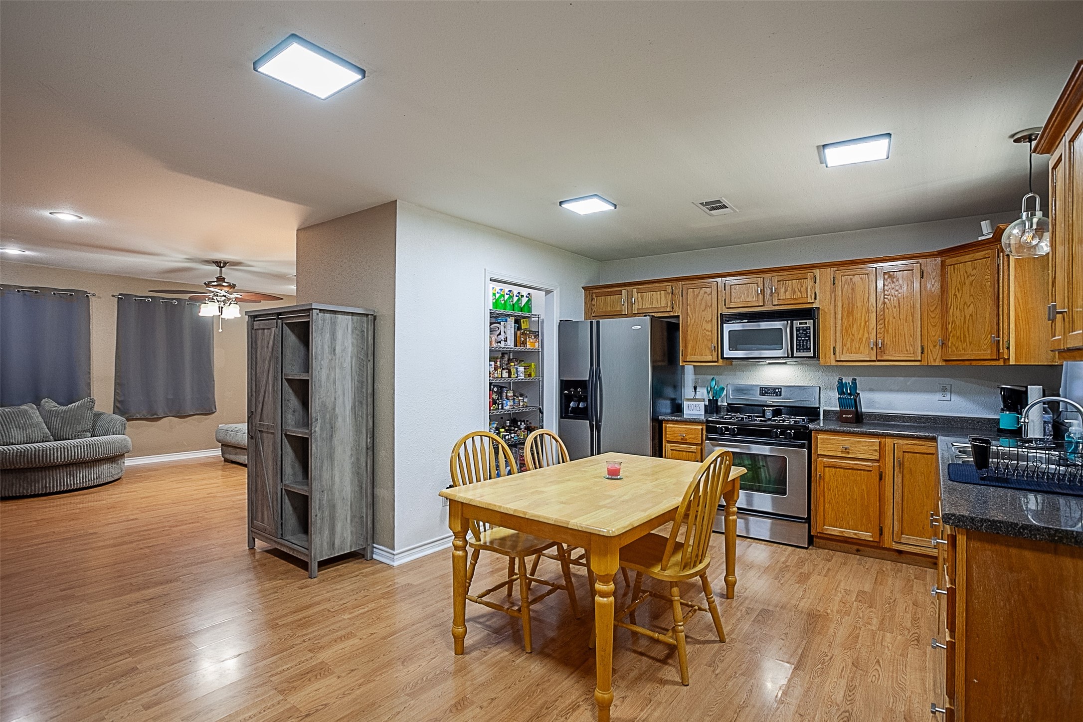 2704 62nd Street Port Arthur, TX 77640 - Photo 7 of 30 a kitchen with stainless steel appliances granite countertop a stove a refrigerator a sink a stove a dining table and chairs with wooden floor