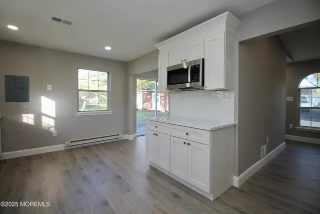 a kitchen with stainless steel appliances white cabinets and wooden floor