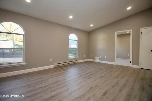 an empty room with wooden floor and windows