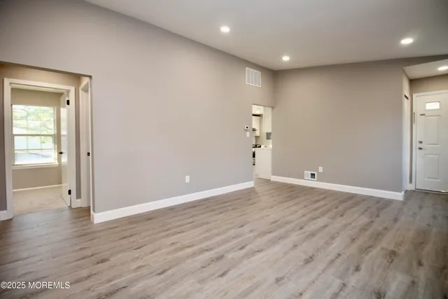 an empty room with wooden floor & closet area
