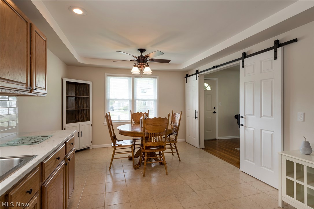 13175 McCracken Road Cleveland, OH 44125 - Photo 8 of 48 Eat-in kitchen dining area with a tray ceiling, a barn door, sink, light tile floors, and ceiling fan
