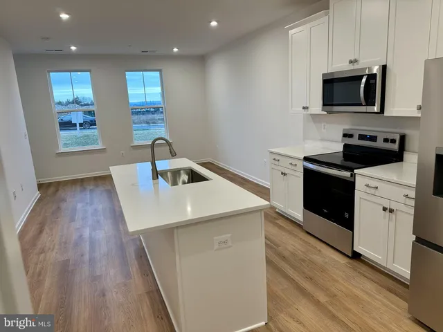 a kitchen with cabinets wooden floor and black appliances