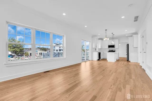 a view of kitchen and empty room with wooden floor and windows