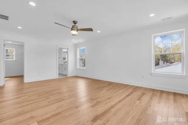 a view of empty room with wooden floor and fan