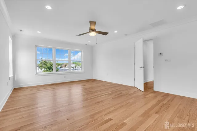 an empty room with wooden floor chandelier and windows