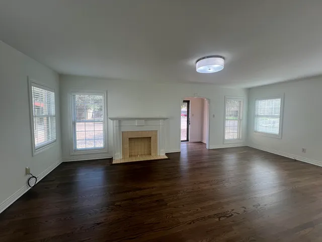 an empty room with wooden floor closet and windows