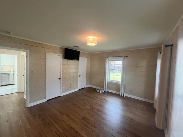 an empty room with wooden floor and windows