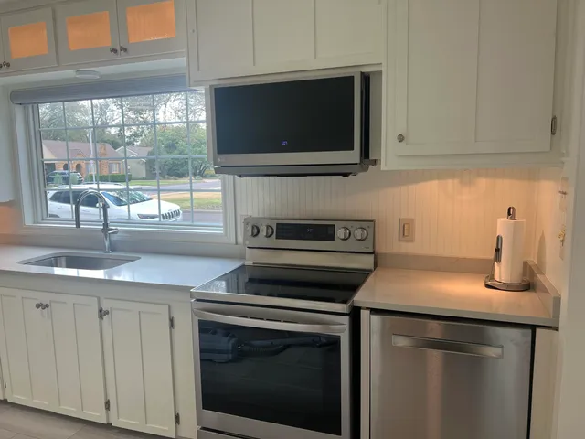 a kitchen with granite countertop a stove sink and microwave