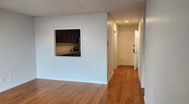 a view of a hallway with wooden floor and a bathroom