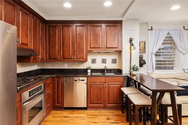 a kitchen with stainless steel appliances granite countertop a stove top oven a sink dishwasher and cabinets with wooden floor