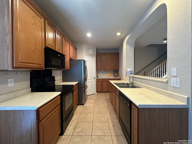 a kitchen with stainless steel appliances granite countertop a sink a stove top oven a refrigerator with wooden cabinets and floor