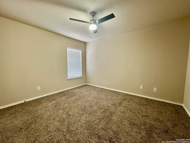 an empty room with a ceiling fan and window
