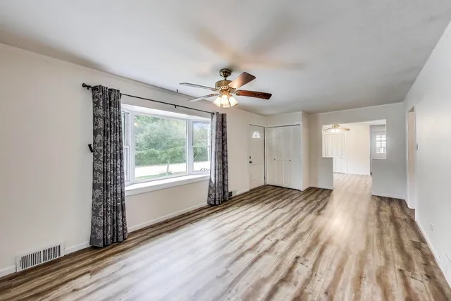 a view of an empty room with a window and wooden floor