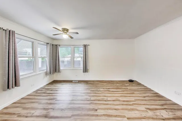 a view of an empty room with a window and wooden floor
