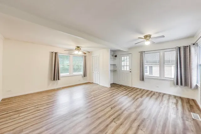 a view of an empty room with a window and wooden floor