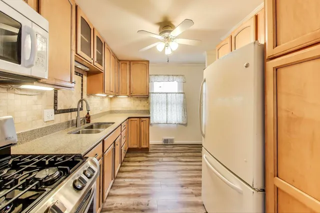 a kitchen with stainless steel appliances granite countertop a sink a stove and a refrigerator