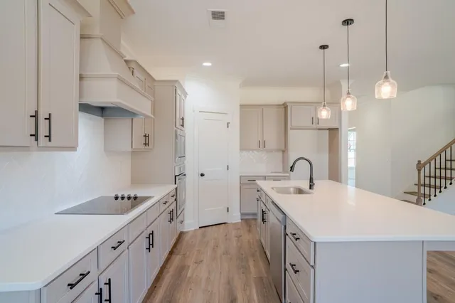 a kitchen with stainless steel appliances a sink a stove a microwave a center island and cabinets