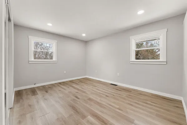 an empty room with wooden floor and windows