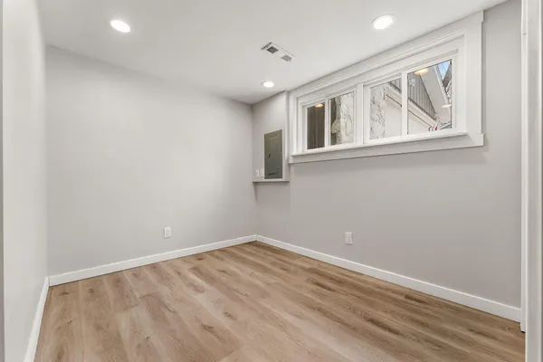a view of empty room with wooden floor and fan