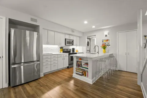 a kitchen with kitchen island wooden floors appliances and cabinets