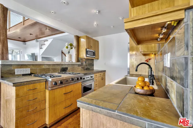 a kitchen with stainless steel appliances granite countertop a sink a stove and a wooden floors