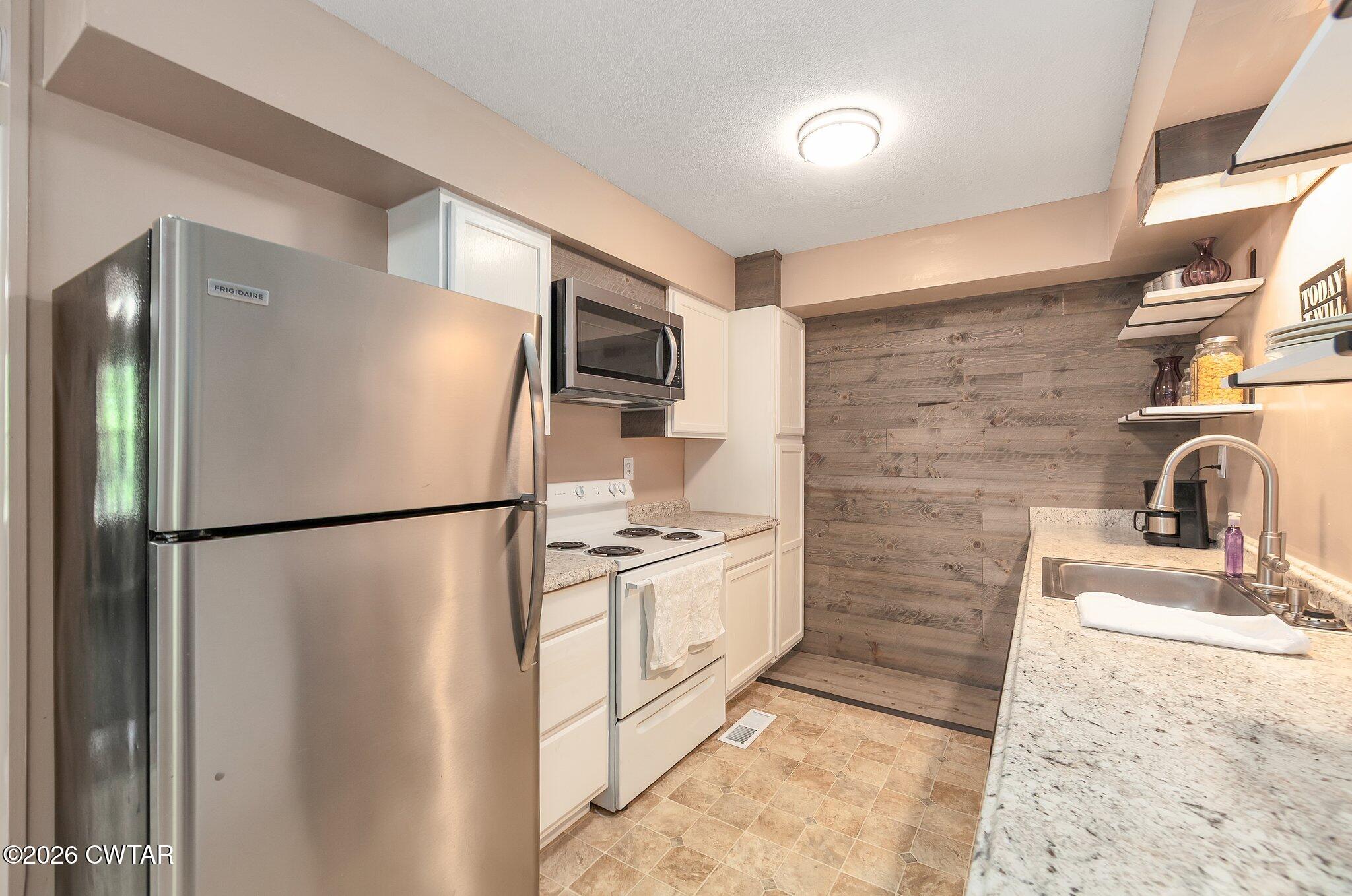 101 Wilde Road Pinson, TN 38366 - Photo 6 of 16 a kitchen with stainless steel appliances granite countertop a refrigerator a stove a sink and a microwave